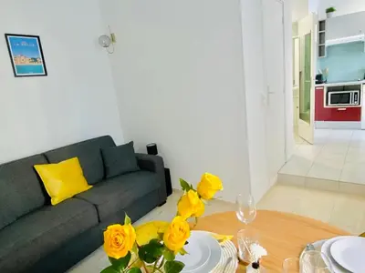 a living room with a couch and a table with yellow roses at Iconic Central Flat in Nice