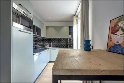 a kitchen with white cabinets and a wooden table at Suite ana in Nice