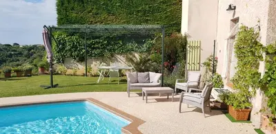 a backyard with a pool and chairs and a table at Studio-mezzanine dans villa in Cagnes-sur-Mer