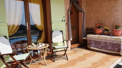 a balcony with chairs and a table and a window at Studio-mezzanine dans villa in Cagnes-sur-Mer