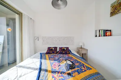 a bedroom with a bed with a colorful blanket at 2 pièces Calme Proche de la mer Parking en sous-sol in Cagnes-sur-Mer