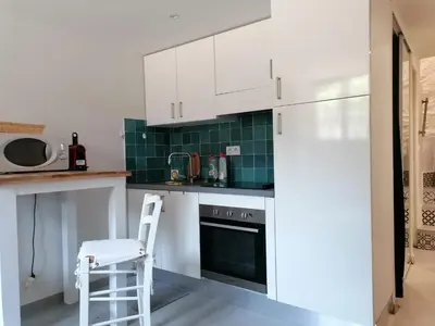 a kitchen with white cabinets and a stool in a kitchen at Joli studio à Nice in Nice
