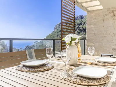 a dining table with plates and wine glasses on a balcony at Apartment Prestige view by Interhome in Èze