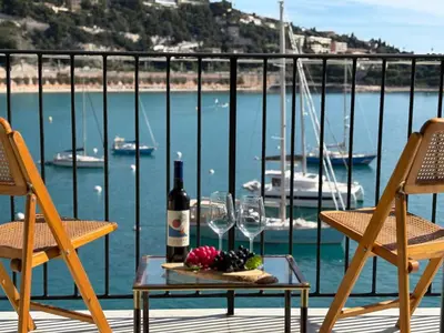 a table with wine glasses and fruit on a balcony at NEPTUNE AP4453 By Riviera Holiday Homes in Villefranche-sur-Mer