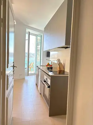 a kitchen with white cabinets and a stove top oven at NEPTUNE AP4453 By Riviera Holiday Homes in Villefranche-sur-Mer