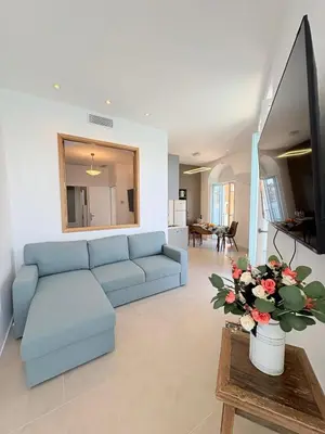 a living room with a blue couch and a tv at NEPTUNE AP4453 By Riviera Holiday Homes in Villefranche-sur-Mer