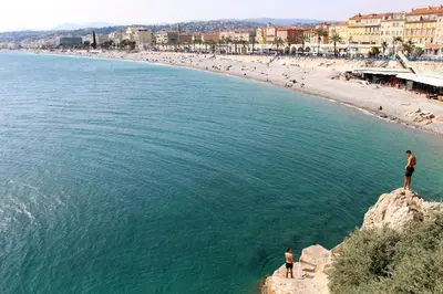 two people standing on a rock overlooking a beach at Cosy Apartment Vauban in Nice