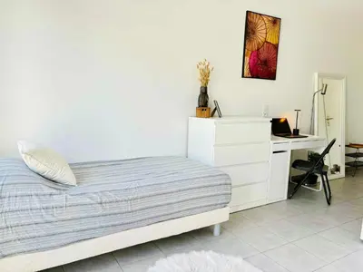 a white bedroom with a bed and a desk at Cosy Apartment Vauban in Nice