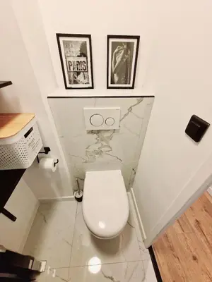 a white toilet in a bathroom with two pictures on the wall at Magnifique vue mer - Piscine -Tennis in Nice