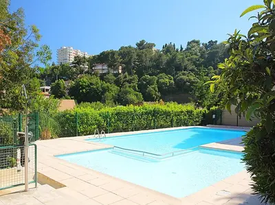 a large blue swimming pool in a yard at Magnifique vue mer - Piscine -Tennis in Nice