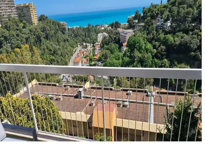 a tennis court with a net and some trees at Magnifique vue mer - Piscine -Tennis in Nice