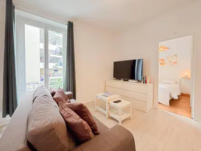 a living room with a couch and a television at Charmant 2P près du Negresco et de la plage - 3pers in Nice