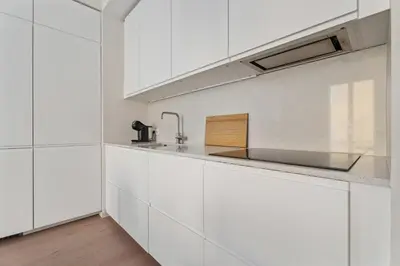 a white kitchen with white cabinets and a sink at Appartement Ostave - Welkeys in Nice