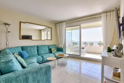 a living room with a blue couch and a large window at T3 avec terrasse vue sur mer à 400m de la plage in Nice