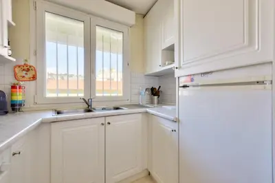 a white kitchen with a sink and a refrigerator at T3 avec terrasse vue sur mer à 400m de la plage in Nice