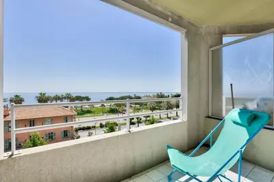 a blue chair on a balcony with a view of the ocean at T3 avec terrasse vue sur mer à 400m de la plage in Nice