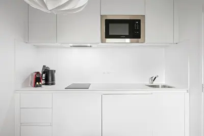 a white kitchen with a microwave and a sink at Vieux Nice - Dernier étage climatisé in Nice