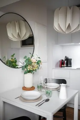 a white kitchen with a table with plates and a mirror at Vieux Nice - Dernier étage climatisé in Nice