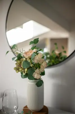 a white vase with flowers in front of a mirror at Vieux Nice - Dernier étage climatisé in Nice