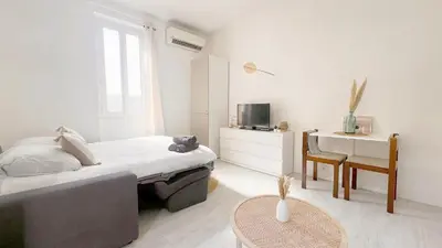 a white bedroom with a bed and a table at La Bella Niçoise in Nice