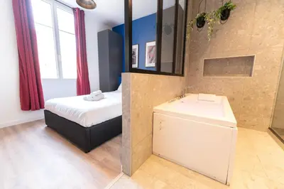 a bedroom with a bed and a sink and a mirror at Nice Centre - Loft - Balnéo 1 in Nice