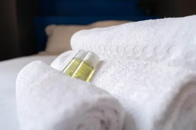 a bottle of oil sitting on top of white towels at Nice Centre - Loft - Balnéo 1 in Nice