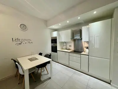 a kitchen with white cabinets and a table with chairs at Suite Doulce France FSHH in Nice
