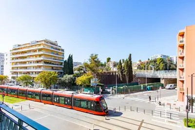 a red train on a street in a city at #37 1BDR Bagatelle, Promenade, sea front Balcony & AC in Nice