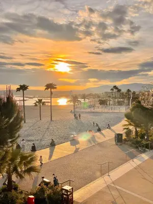 a sunset at the beach with people walking on the beach at Villa La Mer new apartment 75 m2 very quiet in Cagnes-sur-Mer
