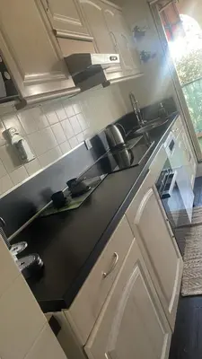 a kitchen with white cabinets and a black counter top at Apartment near Beach-Airport Open 24h in Saint-Laurent-du-Var