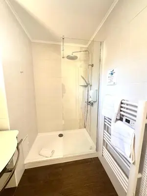 a white bathroom with a shower and a sink at Hotel La Citadelle in Villefranche-sur-Mer