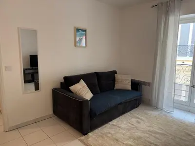 a black couch in a living room with a window at Bel appartement au calme hyper centre Nice in Nice