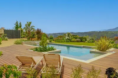 a backyard with a swimming pool with chairs and a wooden deck at Luxury villa piscine chauffée confort exceptionnel in Nice