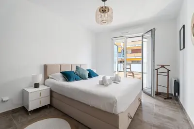 a white bedroom with a large bed with blue pillows at Appartement Amandiers - Welkeys in Cagnes-sur-Mer
