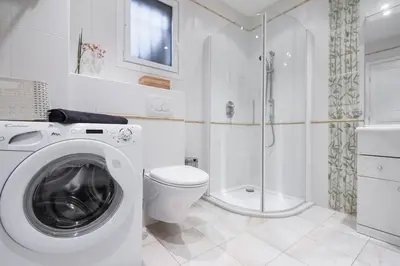 a white bathroom with a washing machine and a toilet at Unique havre de paix in Nice