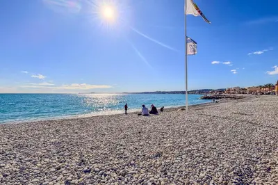a group of people sitting on a beach with a flag at Contemporary 2P Studio Just Steps from the Beach in Cagnes-sur-Mer
