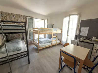 a room with bunk beds and a table and a desk at Alpazur in Nice