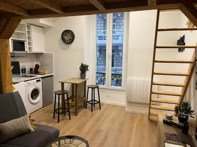 a living room with a staircase and a kitchen at Nice Cosy in Nice