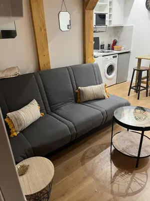 a black couch in a living room with a kitchen at Nice Cosy in Nice