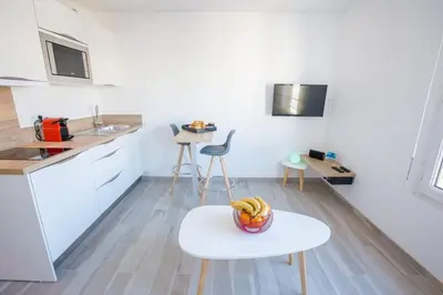 a white kitchen with a bowl of fruit on a table at Joli Studio proche Promenade des Anglais in Nice
