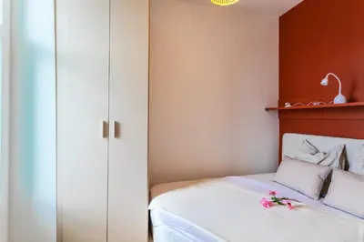 a bedroom with a bed with white sheets and red walls at TERRACOTTA AP4457 By Riviera Holiday Homes in Villefranche-sur-Mer