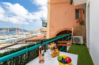a table with wine glasses and fruit on a balcony at TERRACOTTA AP4457 By Riviera Holiday Homes in Villefranche-sur-Mer
