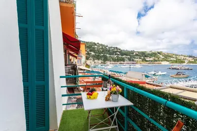 a balcony with a table and a view of the water at TERRACOTTA AP4457 By Riviera Holiday Homes in Villefranche-sur-Mer