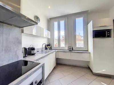a kitchen with white cabinets and a large window at Nestor&Jeeves - PALAIS LASCARIS - Port in Nice