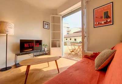 a living room with a couch and a tv and a window at Nestor&Jeeves - PANTAI - Near Beach - Balcony in Nice