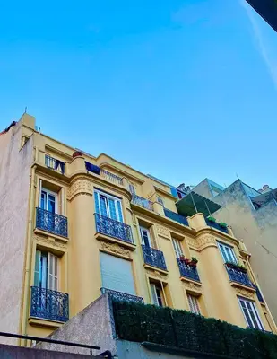a large yellow building with blue balconies on it at Studio Cosy avec vue sur Montagnes, proche Gare in Nice