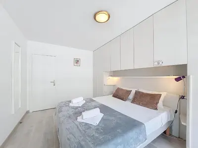 a white bedroom with a large bed with white cabinets at Nestor&Jeeves - CLEA - Terrasse - Central in Nice