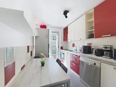a kitchen with red and white cabinets and a wooden table at Nestor&Jeeves - CLEA - Terrasse - Central in Nice