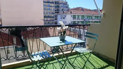 a table and chair on a balcony with a vase of flowers at Moderne Appartement - Port de nice in Nice