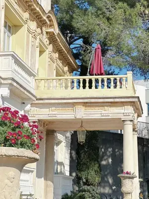 an umbrella on a balcony of a building with flowers at Villa Monique-Parking free in Nice